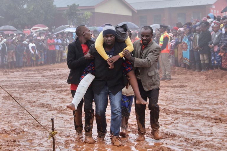 A man carries an injured woman to a tent during a mass funeral for the victims of Storm Freddy in Blantyre, Malawi, March 15, 2023. REUTERS/Eldson Chagara.
