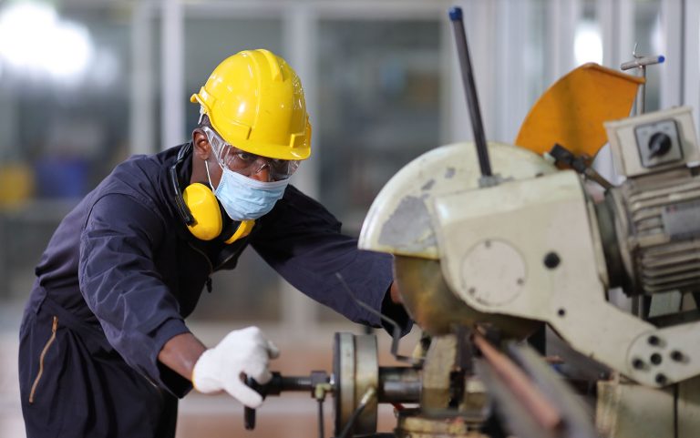 African American mechanic engineer worker wearing facial mask is choosing copper tube for sawing while working in coolant factory under new normal policy during covid-19 pandemic